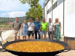 Grupo de personas posando junto a una paella monumental al aire libre
