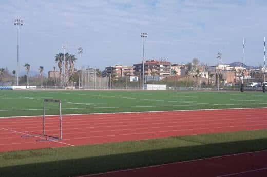 Vista general del campo de atletismo con pista roja y césped verde