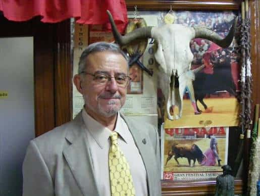 Hombre junto a un cráneo de toro decorativo en la Peña Taurina