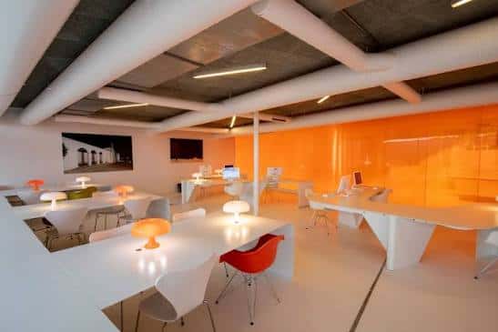 Sala de trabajo moderna con mobiliario blanco y paredes naranjas