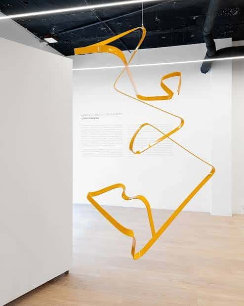 Instalación artística suspendida en amarillo dentro del espacio expositivo