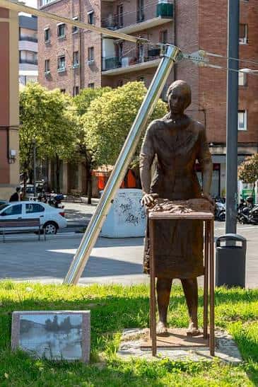 Detalle de la estatua de la lavandera frente a los edificios residenciales