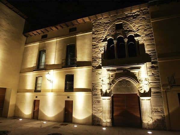 Vista nocturna iluminada de la fachada principal del Palacio del Conde Luna