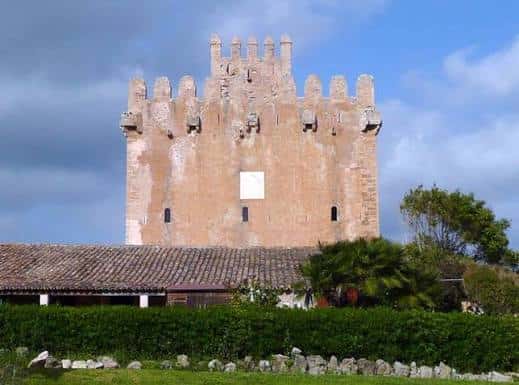 Vista frontal de la Torre de Canyamel con muros medievales y vegetación