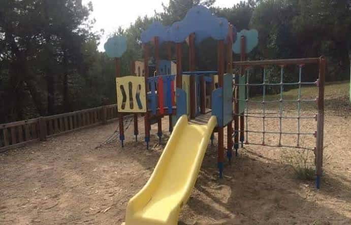Zona de juegos infantiles con tobogán amarillo y estructuras coloridas en el parque