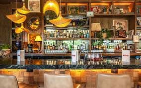 Vista del interior del bar con estanterías de madera y lámparas colgantes