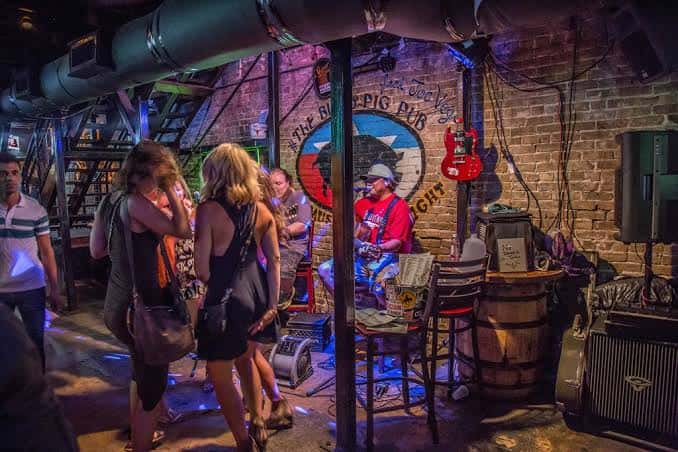 Interior del pub mostrando un músico tocando en vivo frente a una pared de ladrillo