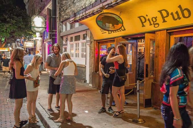 Entrada principal del The Blind Pig Pub por la noche con clientes esperando fuera