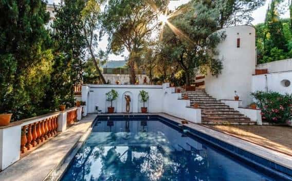 Piscina central con escalinata y vegetación mediterránea al atardecer