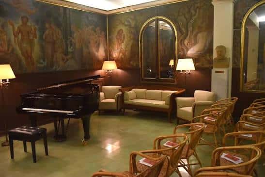 Sala interior con piano de cola, murales clásicos y mobiliario elegante para eventos