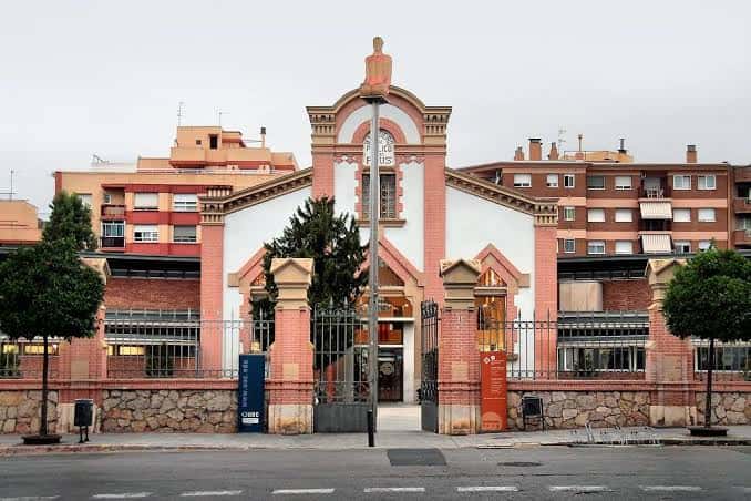 Exterior de la Biblioteca Central de Reus con fachada histórica de ladrillo rosa y entrada principal
