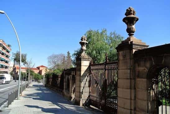 Vista de la entrada principal con muros y portones ornamentales