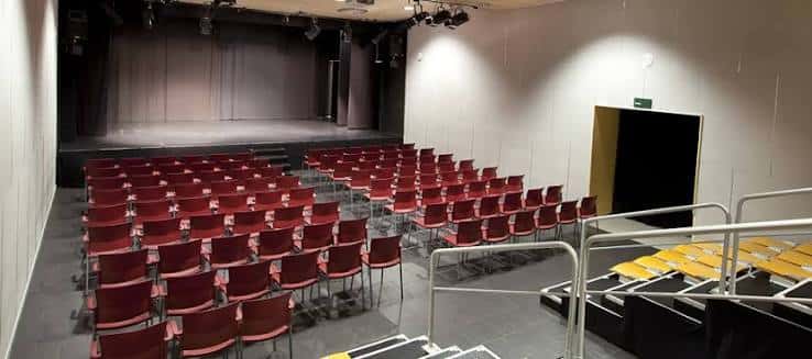 Interior del auditorio con butacas rojas y escenario listo para eventos