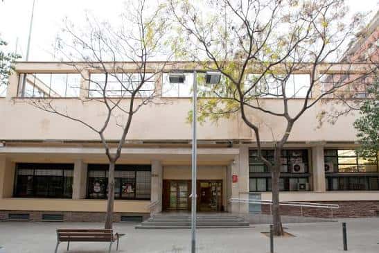 Fachada frontal del edificio rodeado de árboles en un día soleado