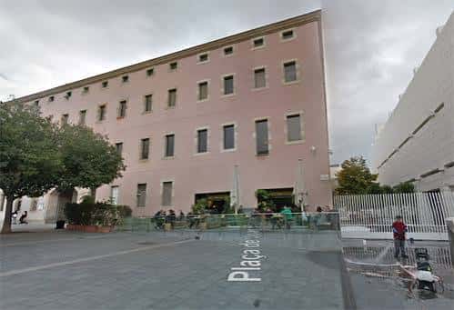 Plaza de Joan Coromines durante el día con terraza y edificio rosa al fondo