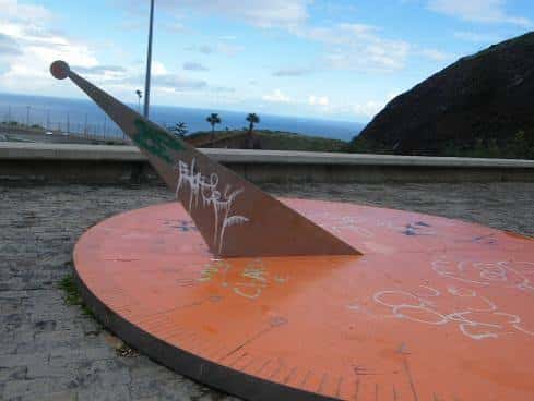 Reloj de sol metálico con vista al mar en el parque