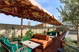 Terraza exterior con sofás naranjas, sombrillas decorativas y vistas urbanas