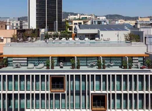 Fachada exterior del edificio Ohla Eixample mostrando su terraza superior con zona de relax