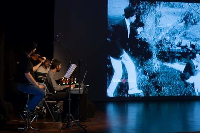 Músicos en vivo acompañando una proyección de cine mudo en el escenario de Caspervek