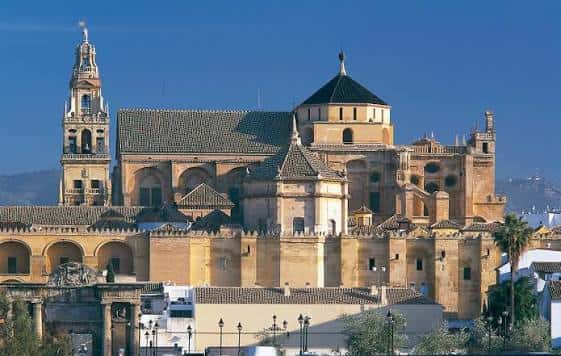 Fachada exterior de la Mezquita-Catedral con la torre campanario bajo un cielo azul