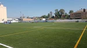 Campo de juego vacío mostrando líneas amarillas y blancas en el césped sintético