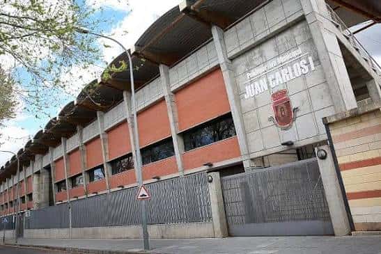 Vista exterior del Polideportivo Rey Juan Carlos I con fachada de hormigón y detalles en ladrillo