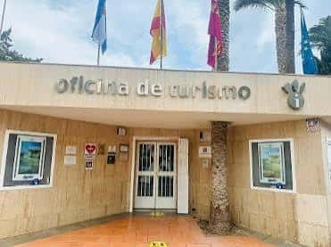 Fachada de la oficina de turismo con banderas y palmeras