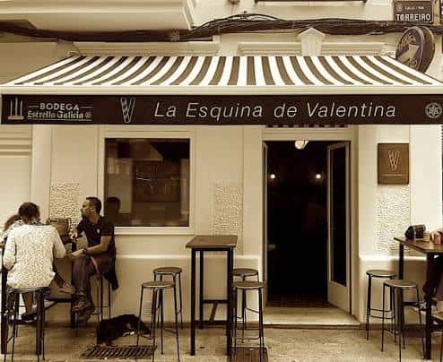 Vista frontal de La Esquina de Valentina con toldo a rayas y clientes sentados
