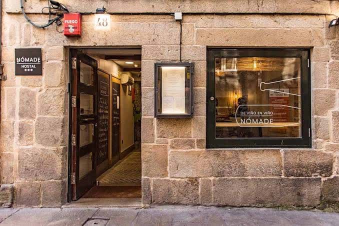 Fachada de piedra del Hostal Nómade con la entrada abierta y el letrero visible