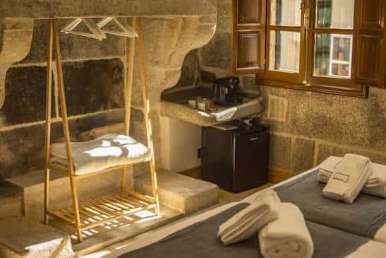 Interior de una habitación con paredes de piedra, cama doble y detalles rústicos