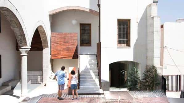 Patio interior con arcos de piedra y escalera moderna que conecta niveles del edificio