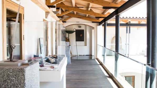 Pasillo interior con vigas de madera expuestas y vitrinas de exposición