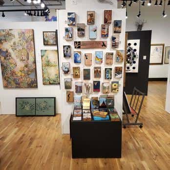 Exposición de obras de arte en las paredes y mesas de la galería
