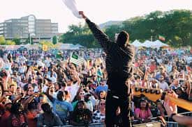 Artista en el escenario del Austin Reggae Festival saludando a una multitud masiva al atardecer