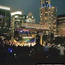 Escenario nocturno del Austin Reggae Festival con skyline de Austin iluminado al fondo