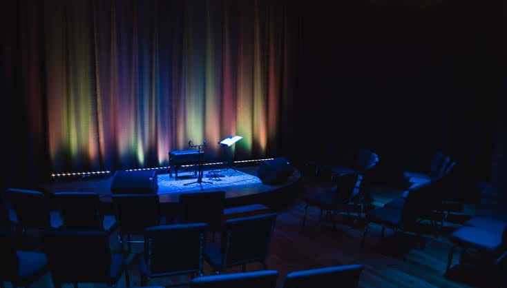 Escenario vacío del auditorio con cortinas de fondo y luces de ambiente