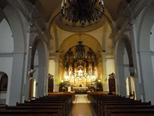 Interior del santuario mostrando el altar principal ornamentado y las bancadas de madera