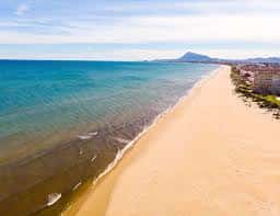 Vista aérea de una extensa playa con el mar en calma y edificios al borde