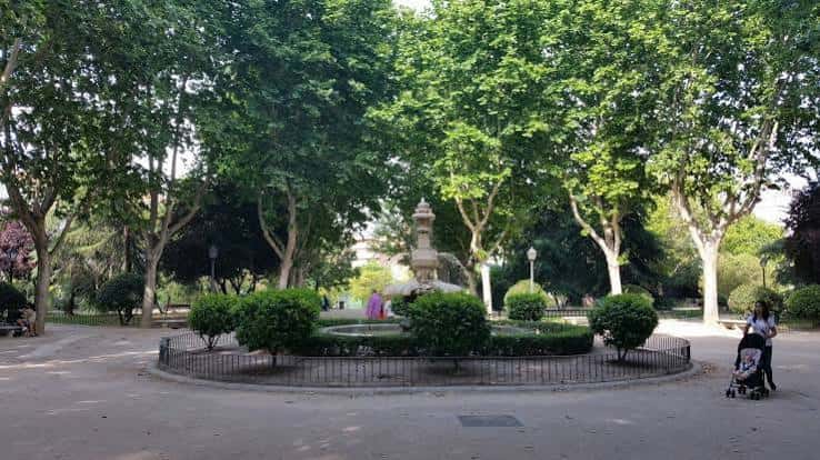 Vista general del parque con la fuente al centro y senderos arbolados
