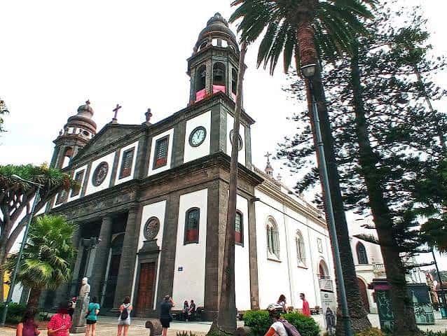 Fachada de la iglesia en Plaza de Tejina con palmeras y gente caminando
