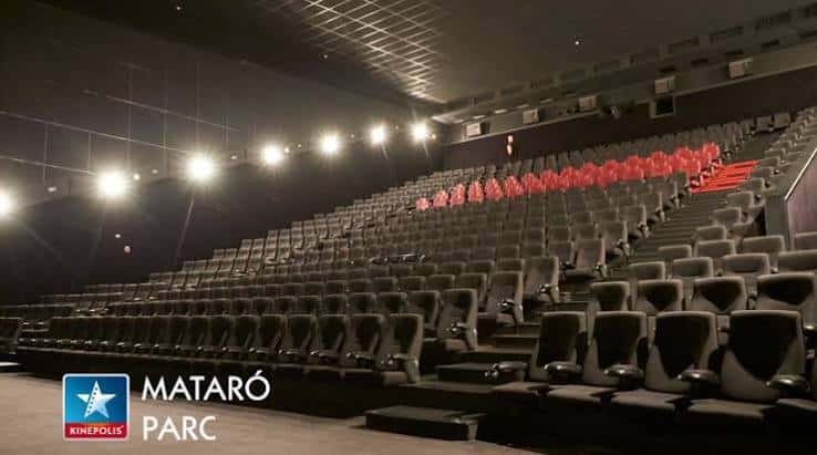 Interior de una sala de cine con butacas grises y rojas dispuestas en gradas