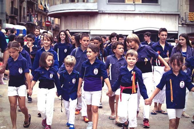 Niños y jóvenes de la Colla Xiquets del Serrallo caminando juntos en formación durante un evento cultural
