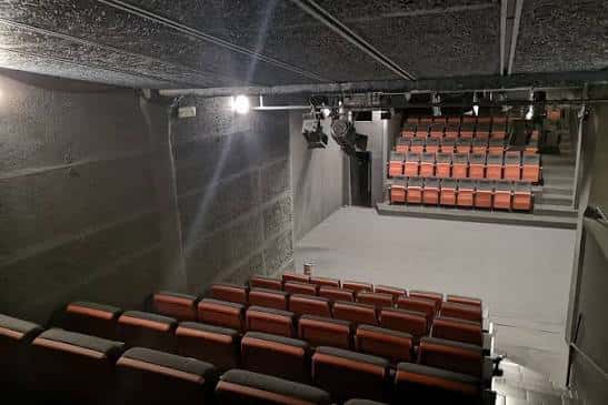 Interior del auditorio con butacas naranjas y escenario