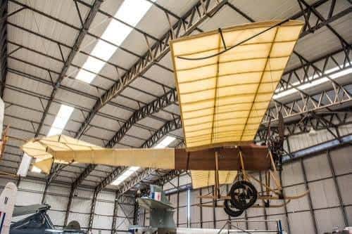 Interior del hangar con avión antiguo colgado del techo