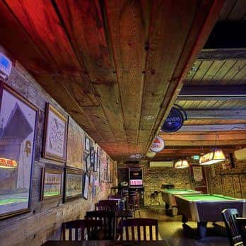 Interior del bar con techo de madera, mesa de billar y decoración temática