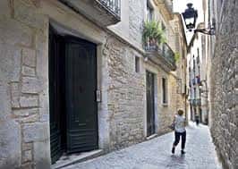 Callejón empedrado con edificios de piedra y una persona caminando