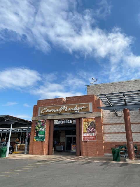 Vista exterior del Central Market en Austin bajo un cielo azul con nubes