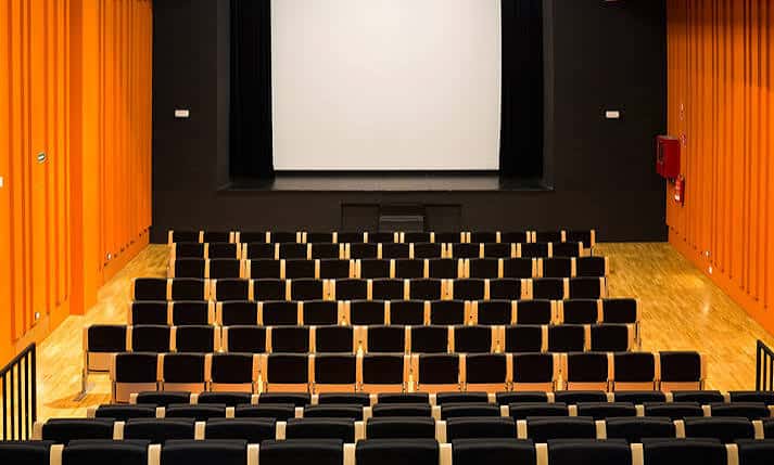 Vista frontal del escenario con pantalla blanca y butacas vacías