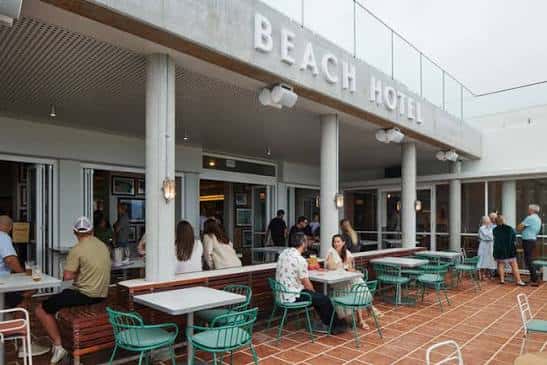 Terraza exterior del Beach Hotel con clientes sentados en mesas verdes