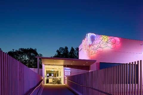 Vista nocturna del Multi-Arts Pavilion con iluminación de neón